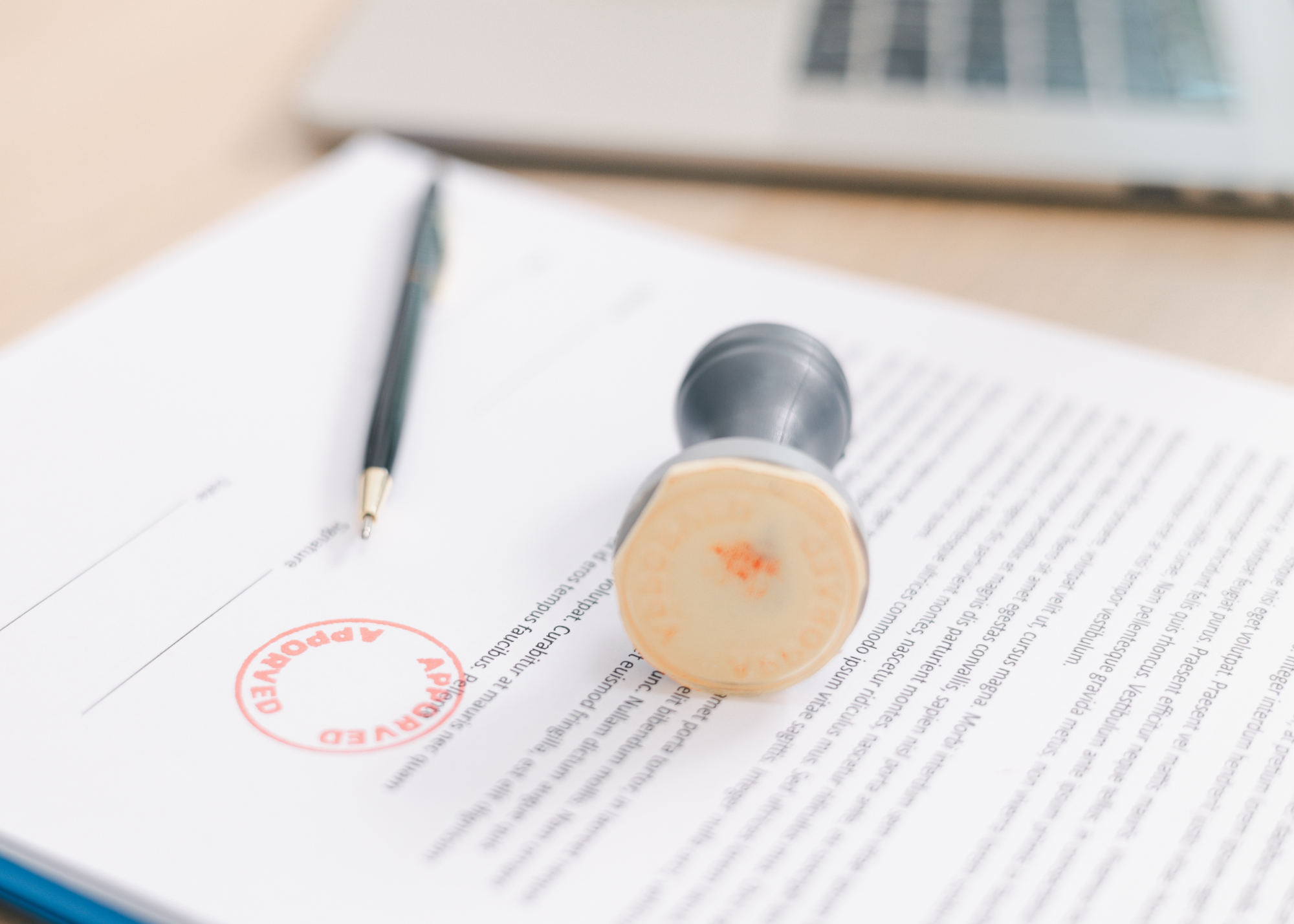 Document on desk with "approved" stamp and pen